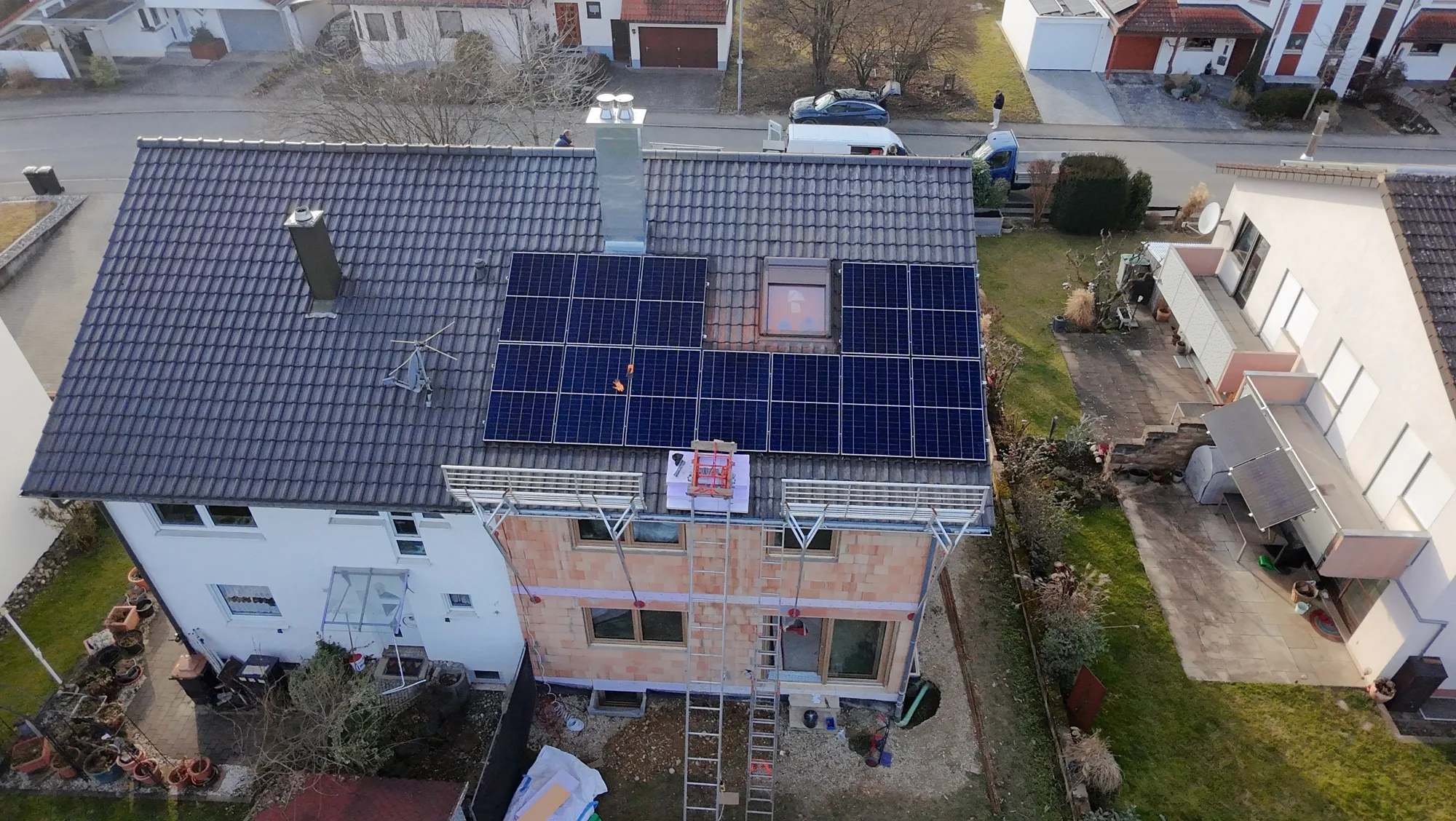 Luftaufnahme einer Photovoltaikanlage auf dem Satteldach eines Wohnhauses während der Montage.